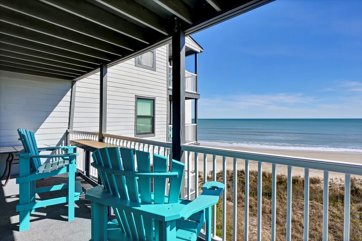 This view from the private balcony features turquoise Adirondack chairs overlooking the ocean. The tranquil setting is ideal for sipping morning coffee, enjoying sunset cocktails, or simply soaking up the stunning seascape and salty breeze.