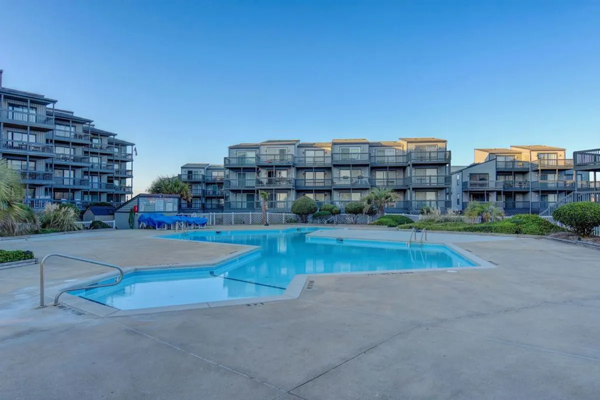 A tranquil community swimming pool surrounded by landscaping and the balconies of nearby buildings—inviting for both relaxation and recreation.