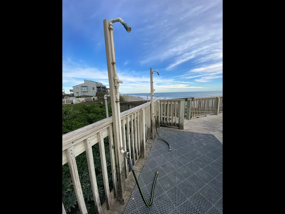 An inviting exterior scene shows outdoor showers, lush greenery, and a glimpse of the ocean, setting the stage for post-swim rinses and relaxed gatherings after beach outings.