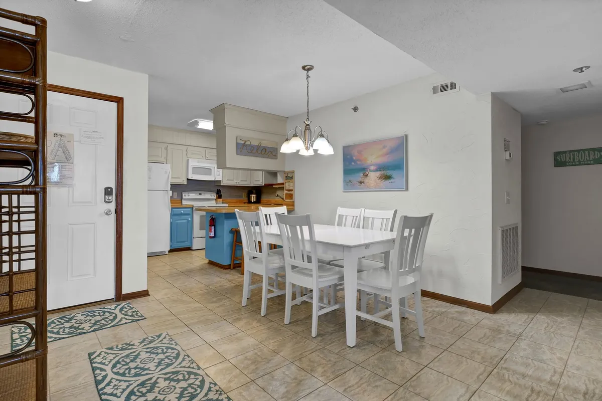 This image centers on a six-person dining table complemented by blue cabinetry and decorative wall art, reflecting a welcoming and stylish dining area. The table is perfect for family meals, celebrations, or casual brunches, and the background suggests a seamless flow into the kitchen space.
